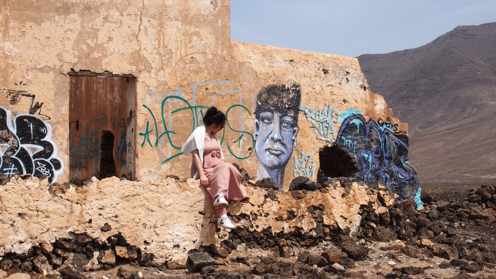 Chacha prend la pose devant un bâtiment décoré par des graffitis
